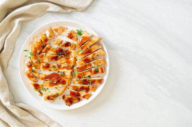 Izgara ballı tavuk göğsü. Beyaz tabakta dilimlenmiş.