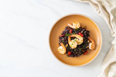 Sarımsaklı ve karidesli kızarmış siyah spagetti.