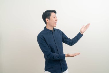 Beyaz arka planda eli işaret eden ya da sunan genç Asyalı adam portresi