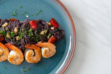 Sarımsaklı ve karidesli kızarmış siyah spagetti.