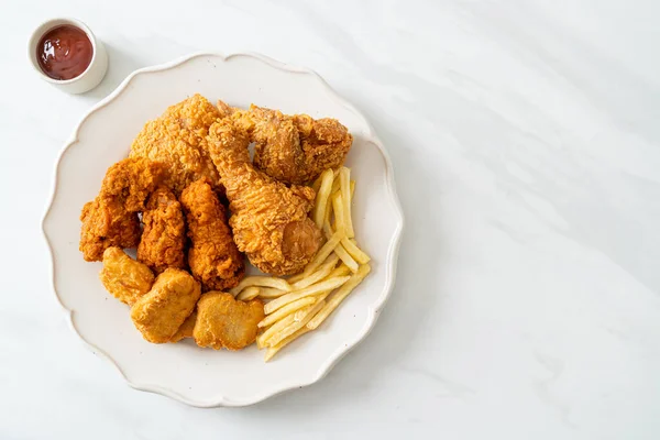 fried chicken with french fries and nuggets on plate - unhealthy food