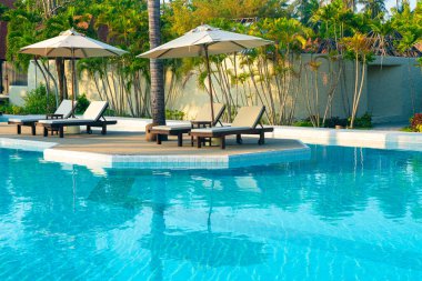 Okyanus geçmişi olan yüzme havuzunun etrafında havuzu olan şemsiyeler - tatil ve tatil kavramı