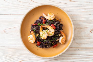 Sarımsaklı ve karidesli kızarmış siyah spagetti.