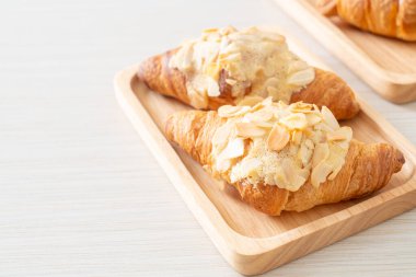 Kremalı kruvasan ve ahşap tabakta badem.