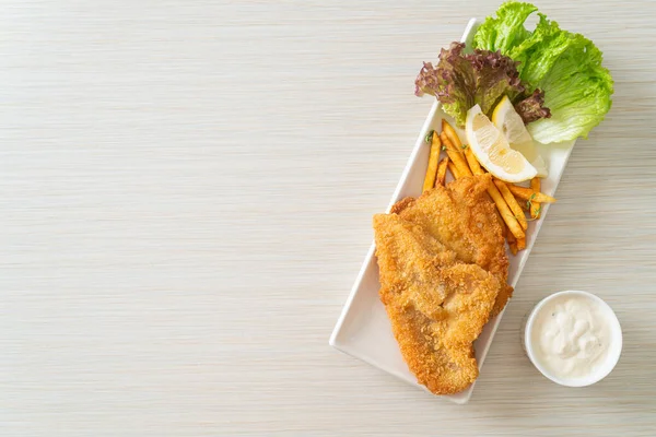fish and chips - fried fish fillet with potatoes chips and lemon on white plate