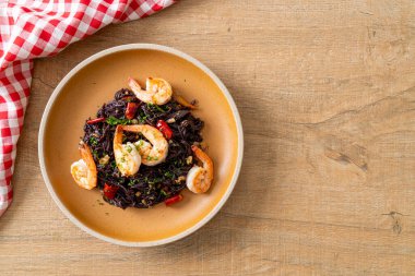 Sarımsaklı ve karidesli kızarmış siyah spagetti.