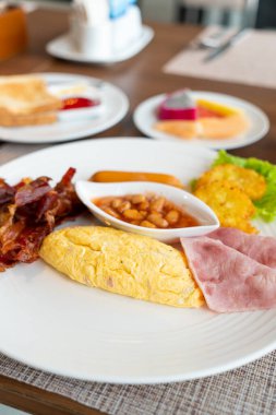 breakfast set - omelette, bacon, ham, sausages, fresh vegetable salad on plate in morning time - Hotel breakfast set concept
