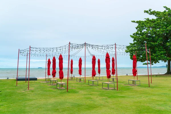 red umbrella with lighting bulb on yard with sea beach background