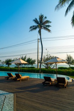 Okyanus geçmişi olan yüzme havuzunun etrafında havuzu olan şemsiyeler - tatil ve tatil kavramı