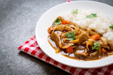 Dilimlenmiş domuz eti, havuç ve soğanlı Japon körili pilavı. Asya usulü.
