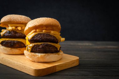 Peynirli ve patates kızartmalı hamburger veya sığır burger. Sağlıksız yemek tarzı.