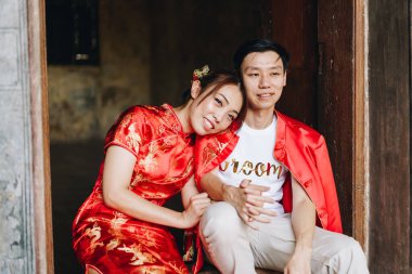 Mutlu genç Asyalı çiftler geleneksel Çin elbiseleriyle sevişir. Kırmızı, geleneksel bayramın ana rengidir. Buna Çin 'de düğün de dahil..