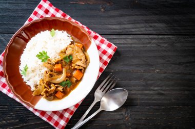 Dilimlenmiş domuz eti, havuç ve soğanlı Japon körili pilavı. Asya usulü.