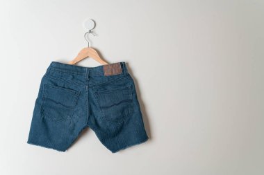 Duvarında ahşap askılı kısa pantolon.