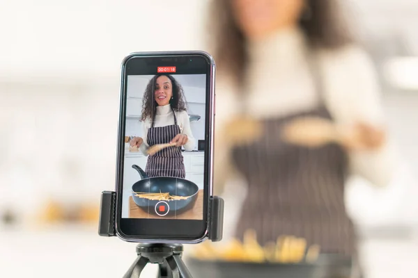 Latin woman shooting video and cooking at the kitchen for share on blog