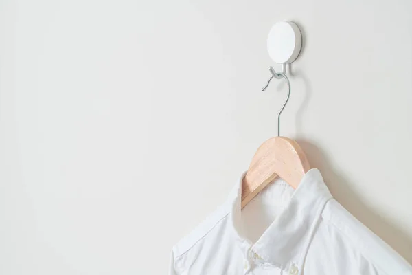 hanging white shirt with wood hanger on wall