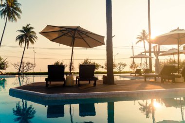 Okyanus geçmişi olan yüzme havuzunun etrafında havuzu olan şemsiyeler - tatil ve tatil kavramı