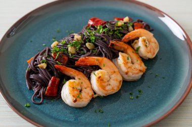Sarımsaklı ve karidesli kızarmış siyah spagetti.