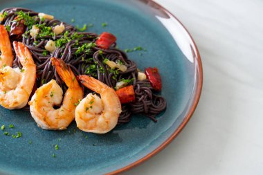 Sarımsaklı ve karidesli kızarmış siyah spagetti.
