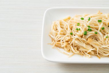 Karıştırılmış altın iğneli mantar, beyaz tabakta tereyağı.