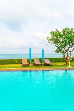 Sandalye havuzu ve şemsiyeyle okyanus arka planında yüzme havuzu