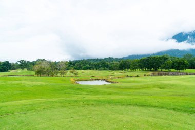 Green and Sand bunkers on Golf course with mountain hill background