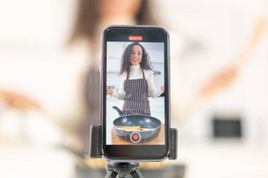 Latin kadın blogda paylaşmak için mutfakta video ve yemek çekiyor.