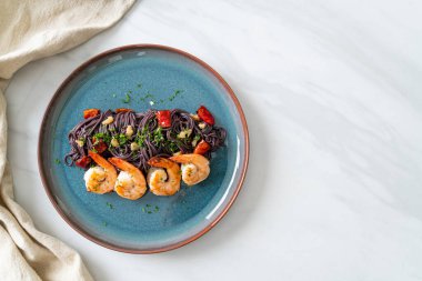 Sarımsaklı ve karidesli kızarmış siyah spagetti.