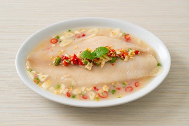 Beyaz tabakta baharatlı limon soslu balık.