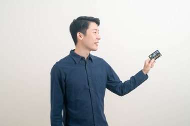 Beyaz arka planda kredi kartı tutan genç Asyalı adam portresi