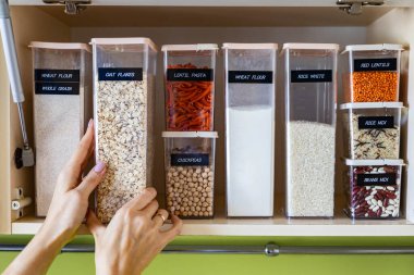 pp kutularındaki saklama makarnası Konmari metodunu mutfaktaki ahşap dolapta kullanır. Ürünleri plastik kutulara yerleştiriyor, sınıflandırıyor ve Kuzey mutfağında isim etiketi takıyor. Genel temizlik, temizlik.
