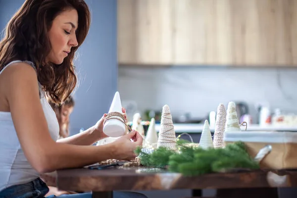 Joven hermosa mujer envolviendo un cono de espuma con hilo de hilo y la elaboración de árbol de Navidad — Foto de Stock