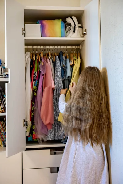 Chica adolescente con el pelo largo enrollado ropa utilizar método Marie Kondos. Colocar ropa en el armario —  Fotos de Stock