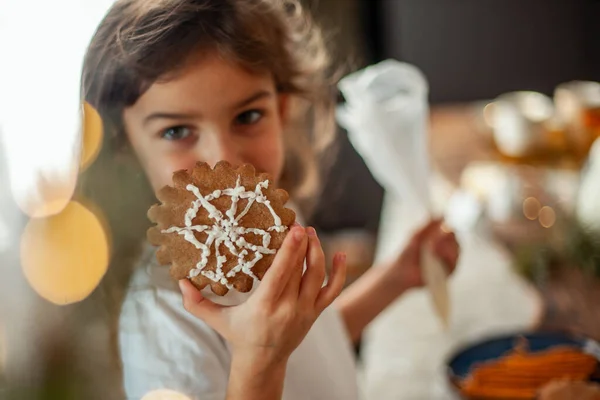 かわいい女の子は砂糖アイシングでジンジャーブレッドを飾る。クリスマスコンセプトの準備. — ストック写真