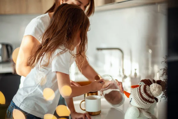 A young beautiful mother and a crying daughter are preparing cocoa in a stylish home kitchen. — Stock Photo, Image