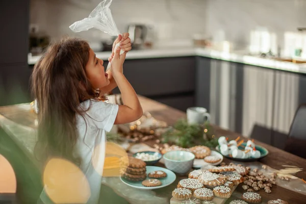작고 귀여운 소녀는 진저브레드를 설탕으로 장식한다. 크리스마스 컨셉트 준비. — 스톡 사진