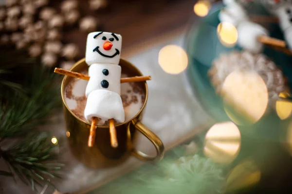 Зефирный снеговик, украшенный глазурью. Золотая кружка с какао и рождественским декором. Пряники в форме снежинки. — стоковое фото