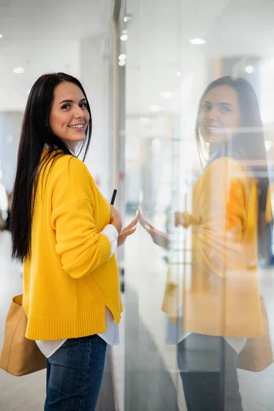 Bella donna shopaholic guardando vetrina boutique di moda che tiene borse della spesa di carta — Foto Stock