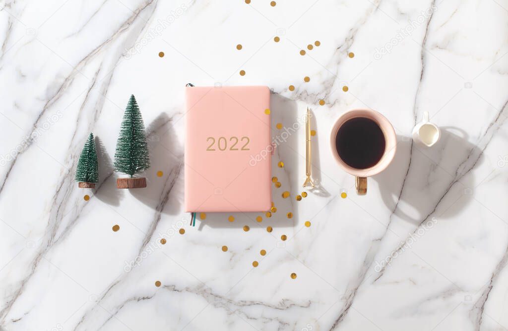 Flat lay composition with New Years decoration, coral colored 2022 diary book and coffee cup