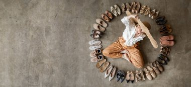 Üstten görünüşlü şık sarışın kadın, yerde oturan ayakkabı seçerken poz veriyor. Gri ayakkabılı birçok kadın ayakkabısı. Tekerlekli, şık ayakkabılar. Topuklu ayakkabılar çok renkli ve zarif.