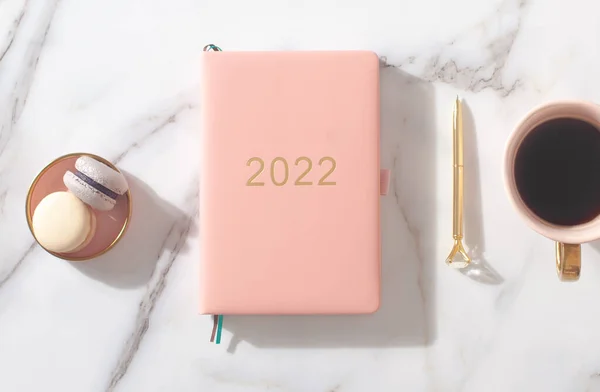 Rosa korallfärgad dagbok för år 2022, penna, kaffe, makaronkaka. Marmor bakgrund — Stockfoto