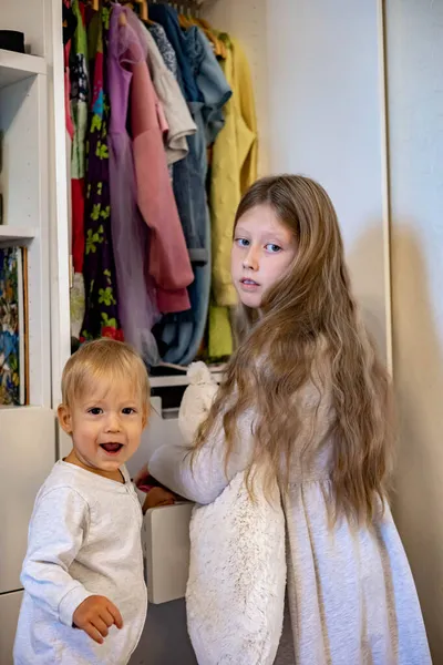 Девочка-подросток с длинными волосами в свернутой одежде использует метод Мари Кондос. Размещение одежды в шкафу — стоковое фото