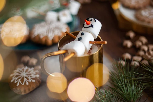 Marshmallow sněhulák zdobený polevou. Zlatý hrnek s kakaem a vánoční výzdobou. Perník ve formě vloček. — Stock fotografie