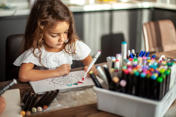 Una piccola ragazza carina disegna un modello di mandala circolare nell'album con pennarelli d'arte. — Foto Stock