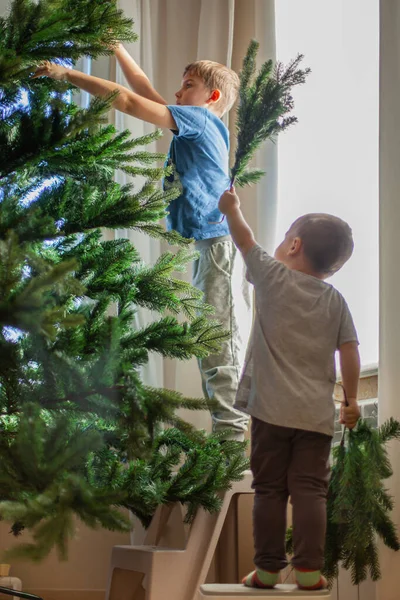 子供たちは自宅のリビングルームの枝から人工のクリスマスツリーを組み立てます。エコクリスマスのコンセプト. — ストック写真