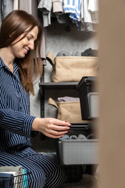 Mujer en pijama cuidadosamente doblado ropa en ecología cesta metálica para un cómodo almacenamiento vertical —  Fotos de Stock