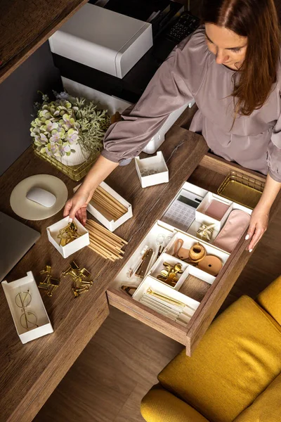 Una mujer está limpiando su lugar de trabajo blanco. Papelería de oro arreglada cuidadosamente. Método de almacenamiento. —  Fotos de Stock