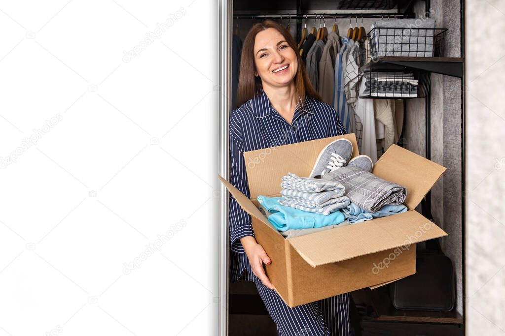 Happy woman taking cardboard box full of clothes for donation charity bazaar or second hand store