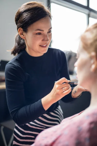 Mulher visagista aplicando maquiagem cosmética para a mulher grávida se preparando. Maquiagem artista trabalhando — Fotografia de Stock