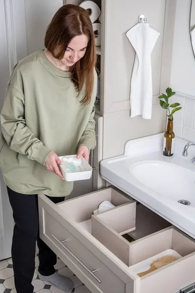 Top view női háziasszony szervez fürdőszoba kényelem és piperecikkek nyitott fiókban mosdó alatt — Stock Fotó